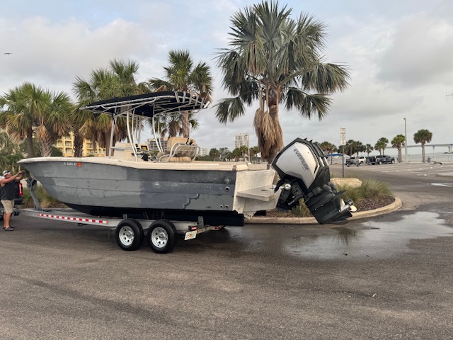 Gray center console fishing boat with an Evinrude outboard on a trailer near the Clearwater waterfront after repair work.