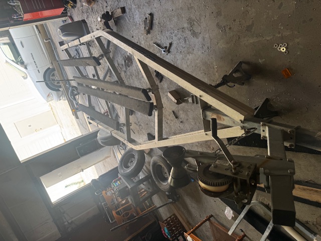 Aluminum boat trailer frame stripped down inside the shop with bunks and rollers being replaced during a rebuild.