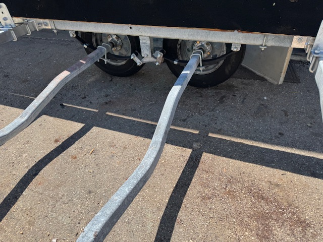 Close-up of a boat trailer's tandem axles, hubs and galvanized fenders after replacement.