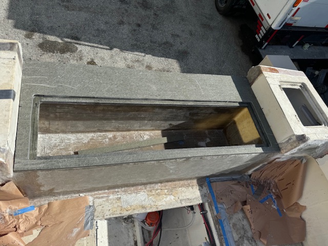 Transom skin cut open on a boat at the Clearwater shop showing the rotted plywood core being removed before new fiberglass laminate goes in.